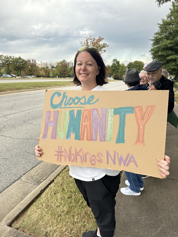 Jamie Stephens at a #NoKings rally in Northwest Arkansas, holding a hand-painted Choose Humanity sign